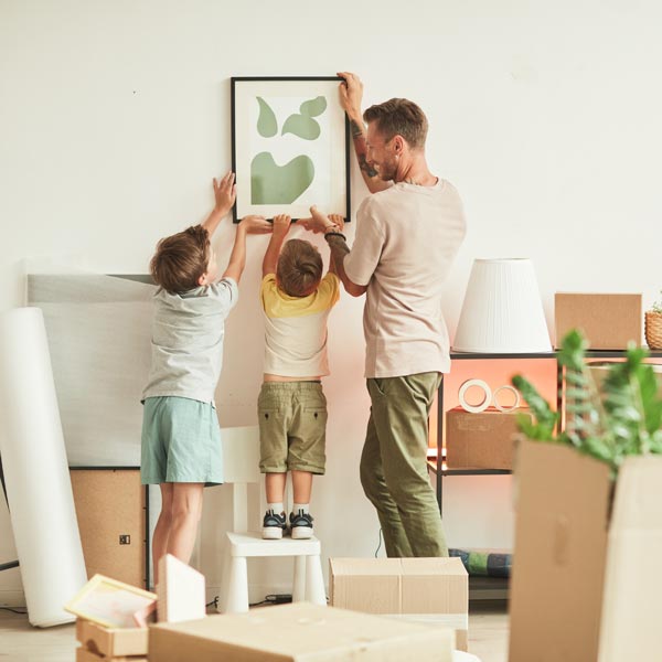 father and two sons hanging art in new home