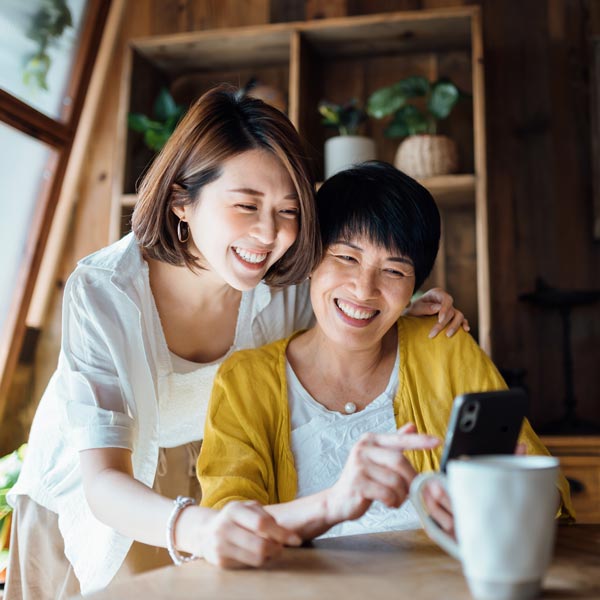 daughter and mother smiling and looking at phone screen